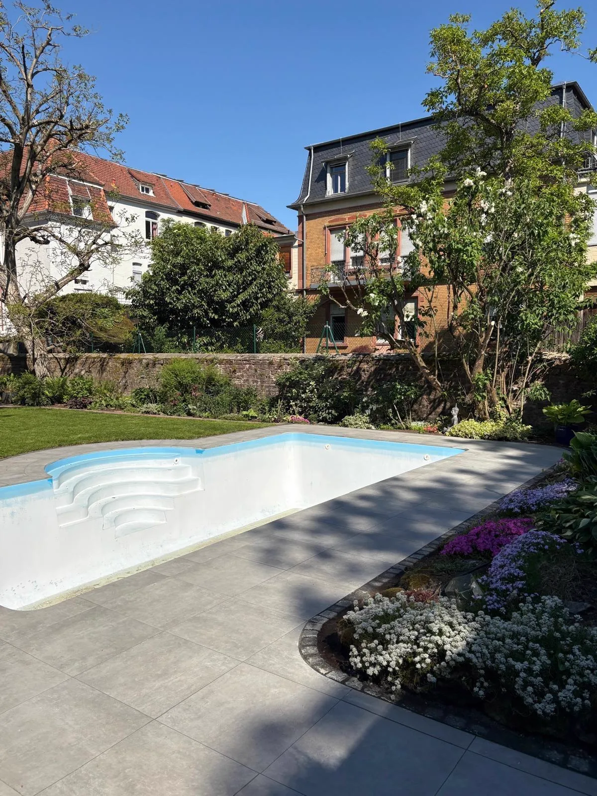 Poolanlage mit Terrasse, Blumenbeeten und Sichtschutz